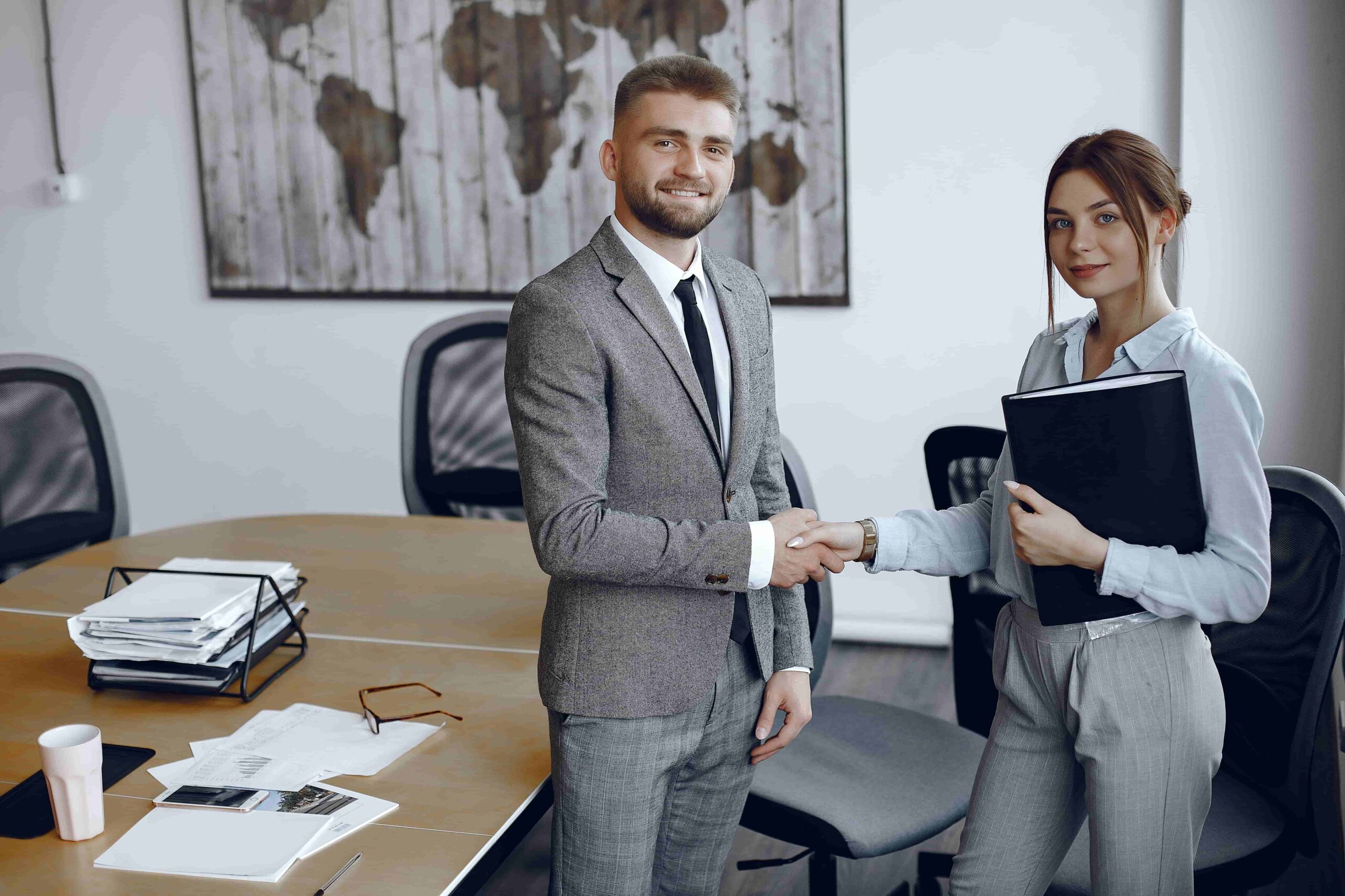 woman-holding-folder-her-hands-businessman-his-office-colleagues-shake-hands (1)